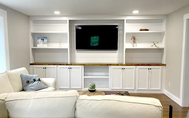 Custom white built-in entertainment center and shelving crafted by expert carpenters for a Boston Metrowest living room.