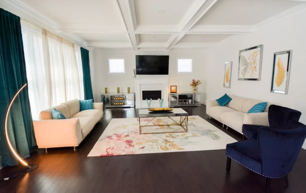 Spacious luxury living room showcasing a custom white fireplace, coffered ceilings, and expansive natural light in a New England home.