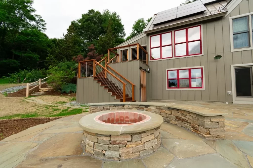 Exterior of a sustainable custom home in New England featuring a natural stone fire pit.